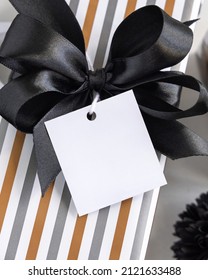 Present With Blank Square Gift Tag And Black Bow Close Up. Gift Boxes Wrapped In Striped Geometric Paper.  Christmas, New Year, Birthday, Anniversary Label Mockup