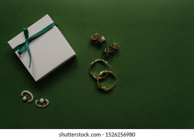 Present Box With Jewelry Nearby On Green Background. Overhead View 