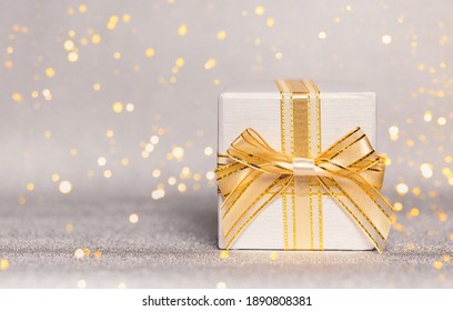 Present box on glittering background. Festive and holiday theme. Christmas or birthday gift. Sales and shopping concept. Copy space