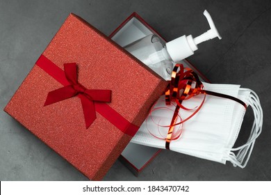 Present, gift box open with hand sanitizing gel and protective masks inside. Dark stone gray background. Holidays, and partys during coronavirus social distance concept. - Powered by Shutterstock