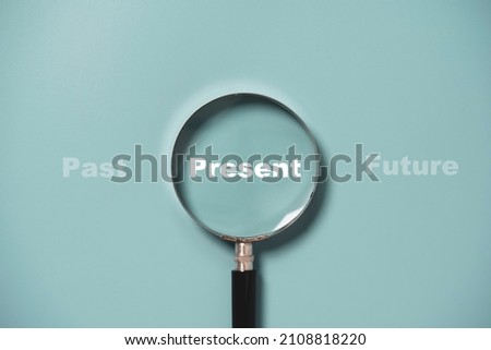 Present wording inside of Magnifier glass on blue background for focus current situation , positive thinking mindset concept.