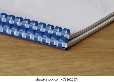 Presentation booklets with blue plastic springs on a wooden table - Shutterstock ID 721628374