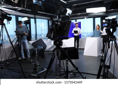 Presenters, Makeup Artist And Video Camera Operator Working In Studio. News Broadcasting