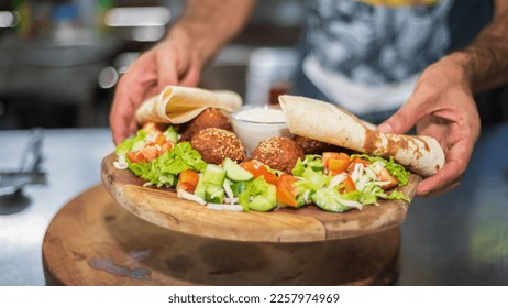 Presenting the middle eastern Lebanese dish Falafel on a wooden plate. tortilla, vegetable salad, and tahini sauce. - Shutterstock ID 2257974969