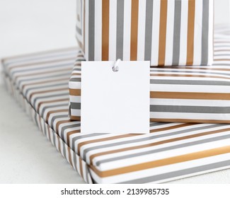 Presents With Blank Square Gift Tag Close Up. Gift Boxes Wrapped In Striped Geometric Paper. Christmas, New Year, Birthday, Anniversary Label Mockup