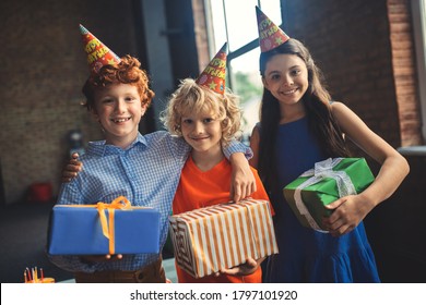 Presents. Three Friends In Bday Hats Holding Presents