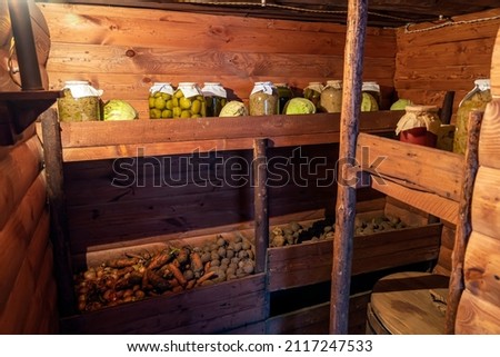 Preservation of vegetables in a warm cellar for the winter period. Glass jars with pickled cucumbers on the shelf.