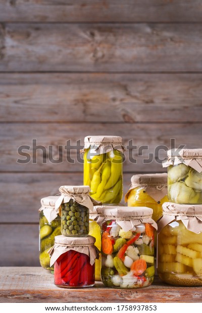 Preserved and\
fermented food. Assortment of homemade jars with variety of pickled\
and marinated vegetables on a wooden table. Housekeeping, home\
economics, harvest preservation \
