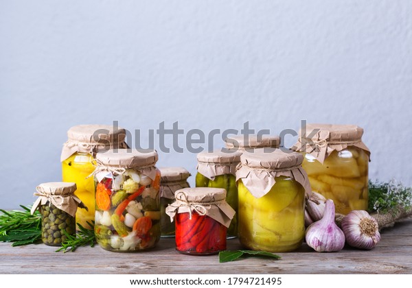 Preserved and\
fermented food. Assortment of homemade jars with variety of pickled\
and marinated vegetables on a wooden table. Housekeeping, home\
economics, harvest preservation \
