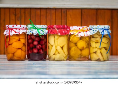 Preserved food in jar, fruit compote on wooden table. Variety of homemade preserved fruit in kitchen. Apricot, cherry, pear, plum and apple compotes