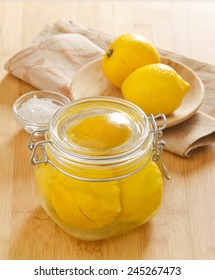 Preserved Lemons With Salt In A Glass Jar On A Wooden Board