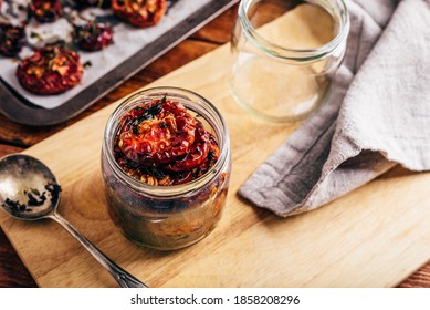 Preserving Of Oven Baked Tomatoes With Olive Oil And Herbs In A Glass Jar