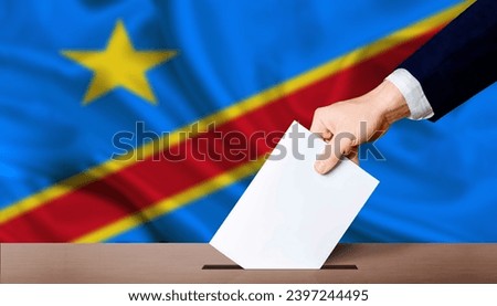 Presidential elections of the Democratic Republic of the Congo. Hand holding ballot in voting ballot box with Democratic Republic of the Congo flag in background