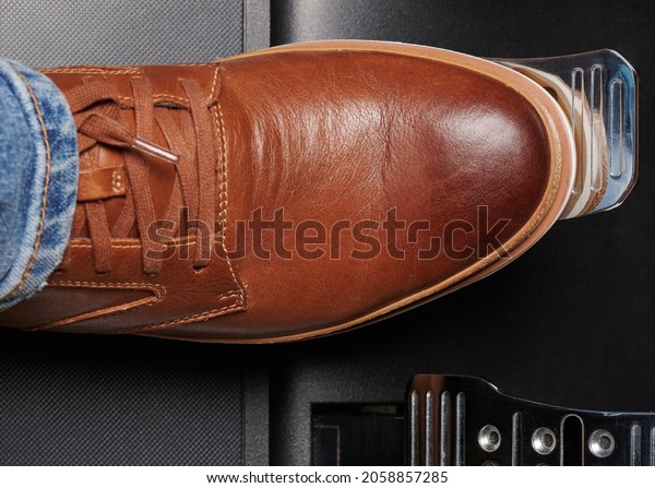 Press brake car pedal via brown leather shoe above\
top view