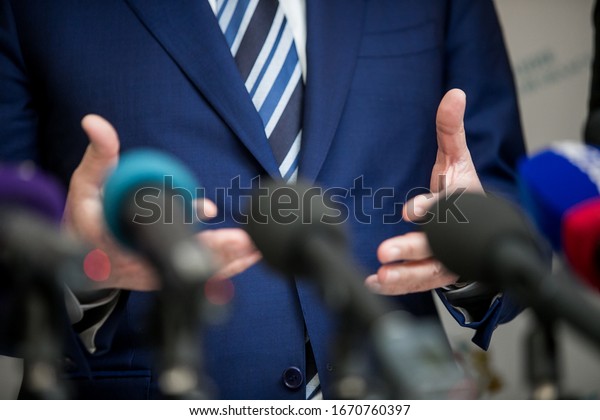 Press conference with media\
microphones held in front of business man, spokesman or\
politician