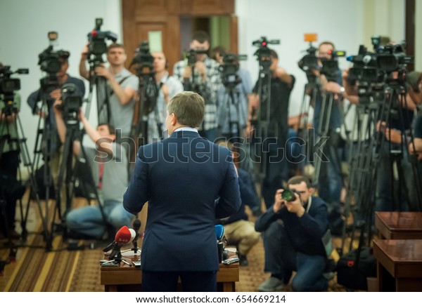 Press conference. Public speaker giving\
talk to Television camera. News conference. An event with a video\
camera. press and media in public news coverage event for reporter\
and mass communication