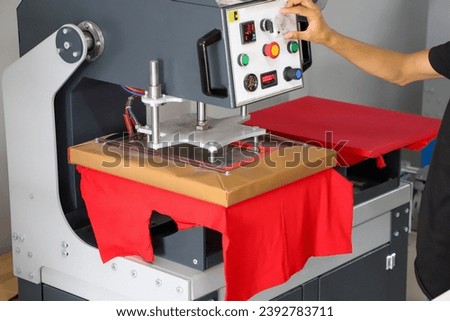 Press printing on colored t-shirts, press for printing images on fabric. Large industrial textile printing machine, when printing textiles for male workers