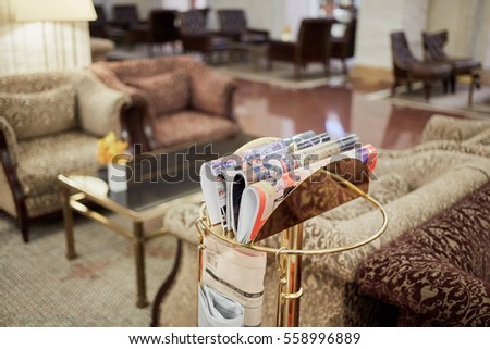 Press rack with magazines and newspapers in hotel hall.