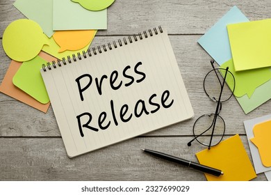 Press Release a lot of stickers are scattered on a wooden background with text on a notepad - Shutterstock ID 2327699029