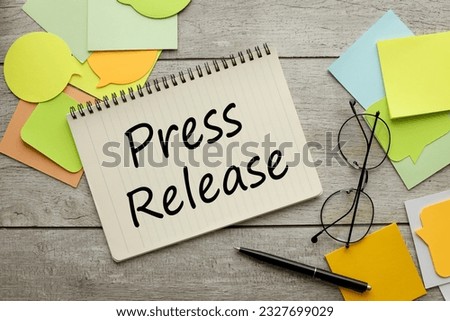 Press Release a lot of stickers are scattered on a wooden background with text on a notepad