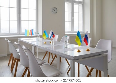 Press Room. Interior Of Room For Diplomatic Meeting Between Representatives Of Ukraine And Russia. Meeting Room Without People With Empty Chairs And Table With Small Flagpoles With National Flags.