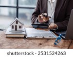 Pressing calculators, hand plans home refinance. House model, buy or rent, calculators on desk. Saving for property purchase, optimal mortgage payment. Tax, credit analysis for financial planning.
