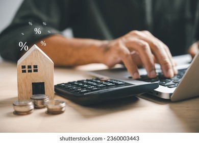 Pressing calculators, hand plans home refinance. House model, buy or rent, calculators on desk. Saving for property purchase, optimal mortgage payment. Tax, credit analysis for financial planning.