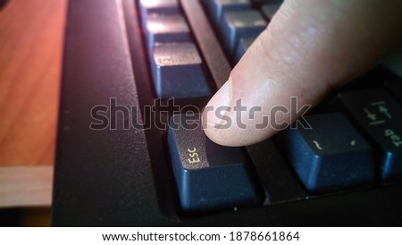 Pressing the Esc key on a computer keyboard. A macro view of an escape button typing with a finger on a computer. Concept of panic, interruption, abort and problem solve.