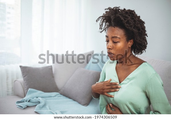 Pressure in the chest. Close-up of a stressed woman\
who is suffering from a chest pain and touching her heart area. A\
stressed woman who is suffering from a chest pain and touching her\
heart area.