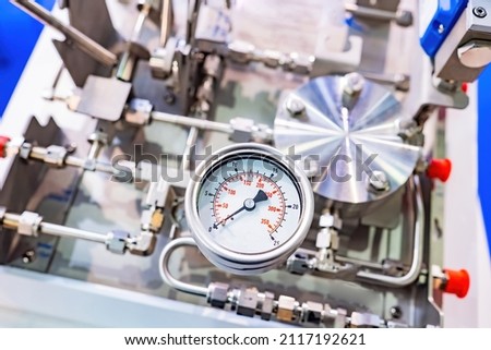 Pressure gauge on production equipment. Close-up pressure sensor. Fragment of production or laboratory equipment. Silver tubes next to mechanical pressure sensor. Industrial equipment.