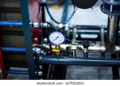 Pressure Gauge Psi Meter In Pipe And Valves Of Water System Industrial Focus Left Closeup White Light Defocus Blur Background.