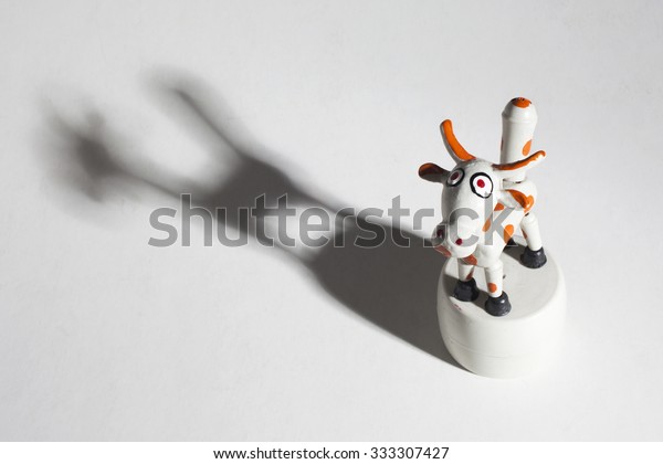 Pressure toy cow with articulated parts. Dramatic\
lighting and shadow.