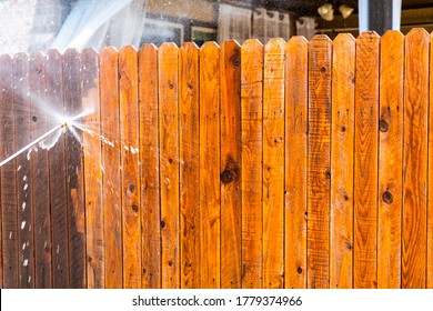 Pressure Washing Wooden Fence In Suburb Neighborhood During Stay At Home Orders For Covid-19 Lockdown Cleaning Surfaces And Home Repairs
