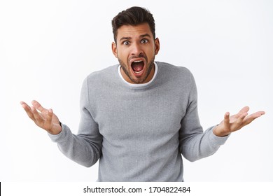 Pressured handsome guy having intense argument, screaming with questioned, frustrated expression, was accused in something bad, try understand what happened, spread hands sideways dismay