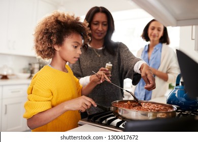 Pre-teen African American Girl Standing At The Hob In The Kitchen Preparing Food With Her Grandmother And Mother, Close Up, Selective Focus