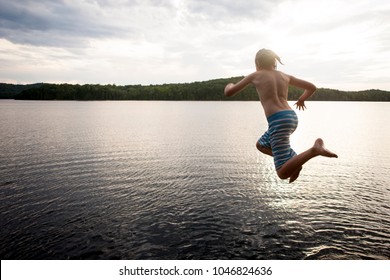 Preteen Boy Jumping Off Cliff Into A Lake.