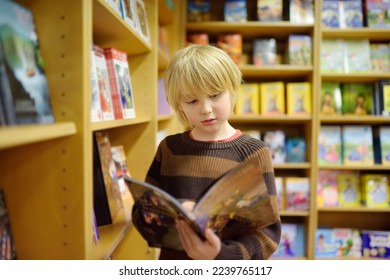 A preteen boy leafing through a book while standing at the bookshelfs in a school library or bookstore. Smart kid reading comics or adventure book - Shutterstock ID 2239765117