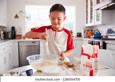 Pre-teen boy making a cake in the kitchen mixing cake mix, smiling, close up - Powered by Shutterstock