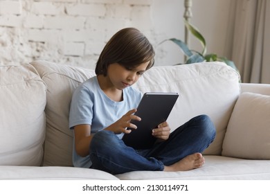 Pre-teen Boy Sit On Sofa Using Digital Tablet, Looks Absorbed Play Video Games On-line, Watch Video Vlog Internet Content Spend Time Alone At Home. Bad Posture And Habit, Modern Gadget Overuse Concept