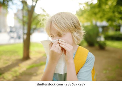 Preteen boy sneezing and wipes nose with napkin during walking in summer park. Allergic child. Sick kids. Treatment of flu season and cold rhinitis - Powered by Shutterstock