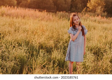 Preteen caucasian girl with long brown hairs walking in summer meadow and dreaming. Little girl deep in thoughts. Mental health and unity with nature concept