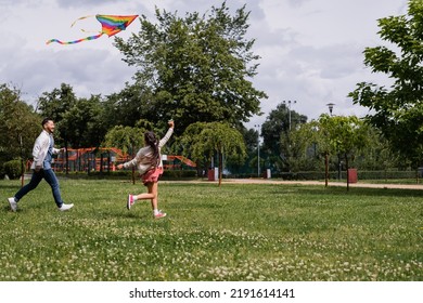 Preteen child holding flying kite near asian dad in park - Powered by Shutterstock