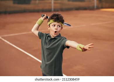 Preteen child in sportswear swinging racket while training on tennis playground in summer
