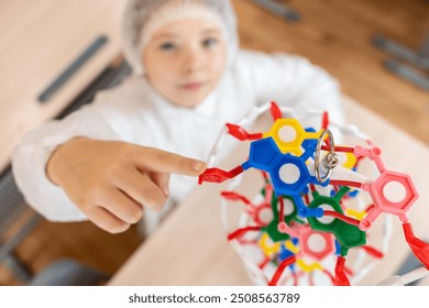 Pre-Teen Female Student Pointing to DNA Model In White Coat At School. selected focus. High quality photo - Powered by Shutterstock