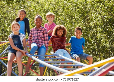 Pre-teen friends sitting on climbing frame in playground