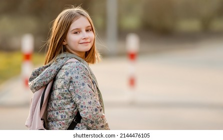 Preteen girl child with backpack outdoors. Pretty schoolgirl going home after class and smiling