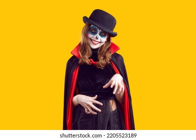 Preteen girl with creative Halloween make-up and wearing dracula cape isolated on orange background. Portrait of smiling child having fun at carnival party. Halloween party concept. Web banner. - Shutterstock ID 2205523189