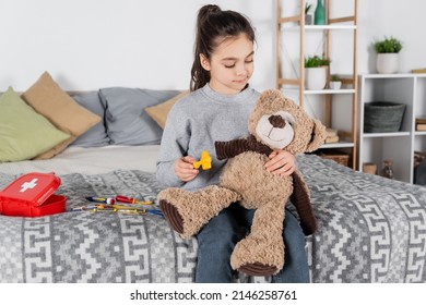 Preteen Girl Examining Teddy Bear With Toy Neurological Malleus In Bedroom