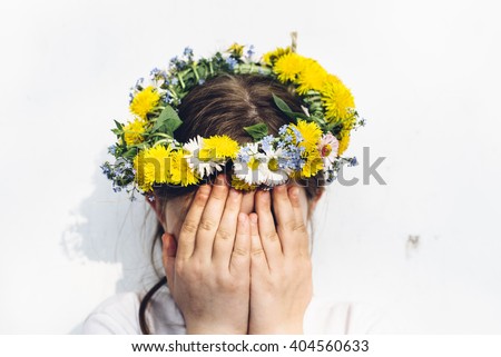 Preteen girl in flower circlet with hands covering her face