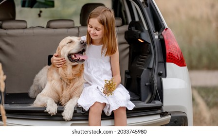 Preteen Girl With Golden Retriever Dog Sitting In Car Trunk Together. Pretty Child Kid Hugging Doggy Pet In Vehicle